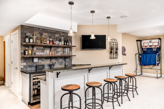 home bar setup in a house, with bar stools and a bar top. There are liquor bottles on shelves.